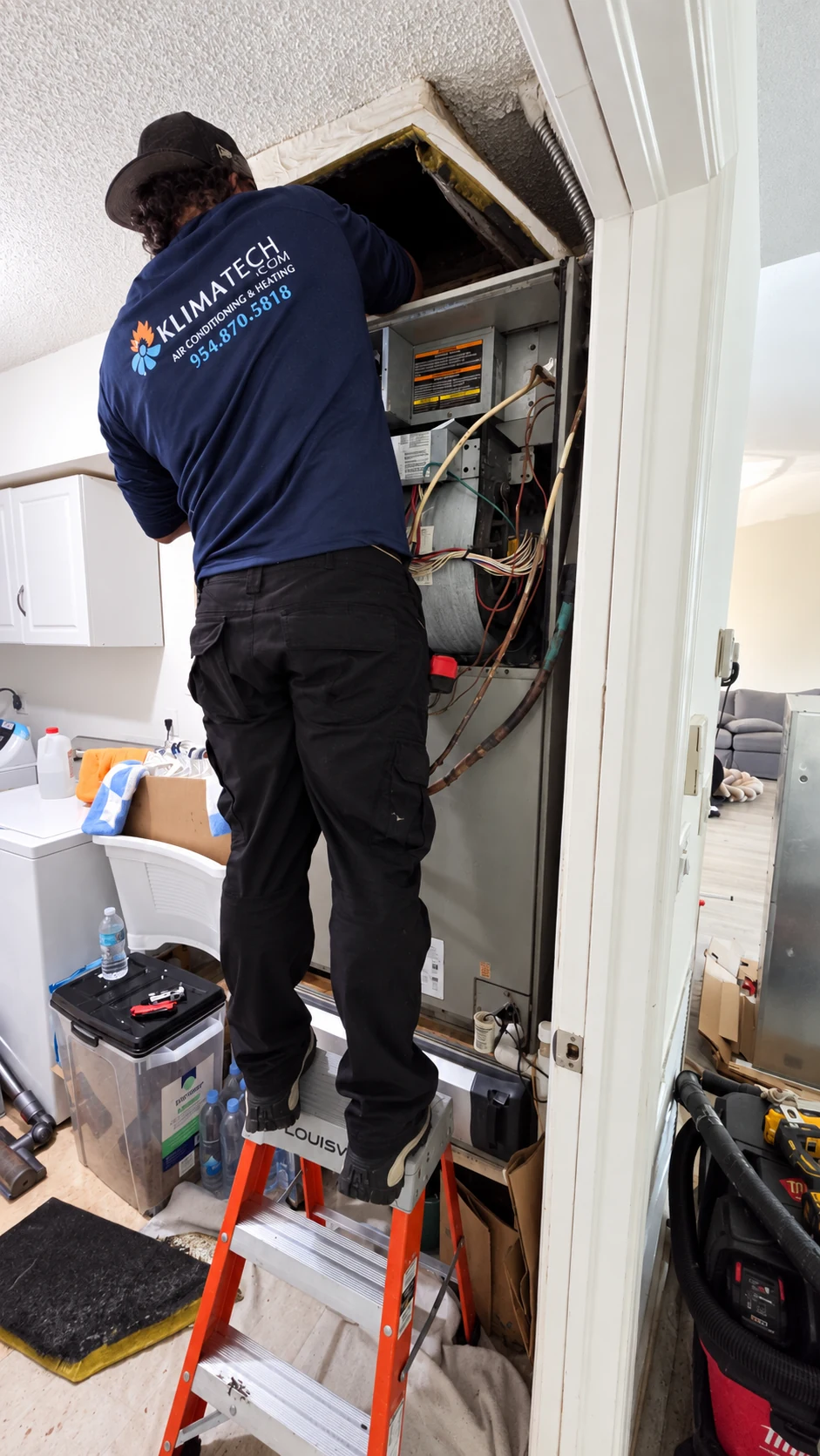 KlimaTech technician servicing an indoor air conditioning unit.