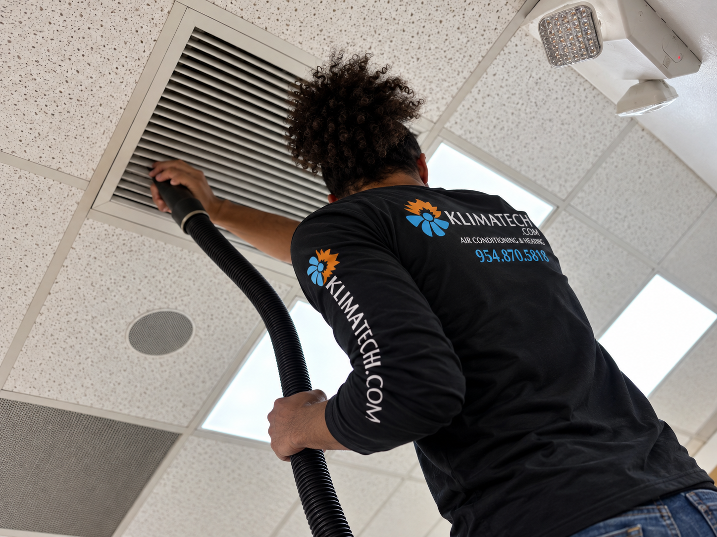 KlimaTech AC maintenance technician inspecting an HVAC system